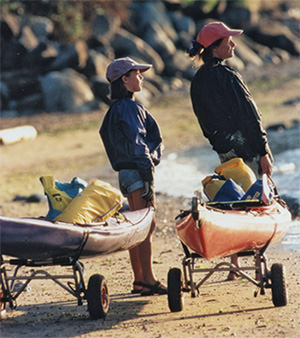 Kayak/Canoe Cart with Tuff-Tire Wheels at the beach with two people holding kayaks